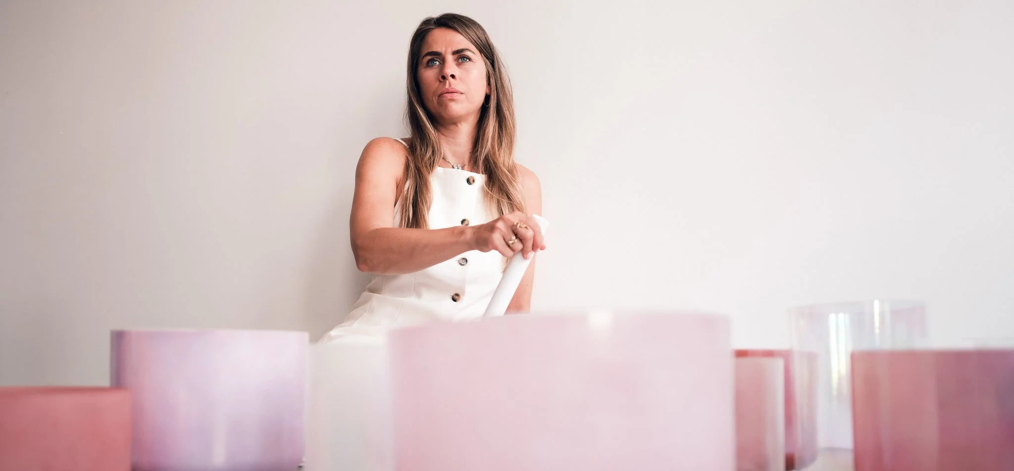 Lydia playing pink and purple Alchemy Crystal Singing Bowls in a seated position – sound healing session-modern background