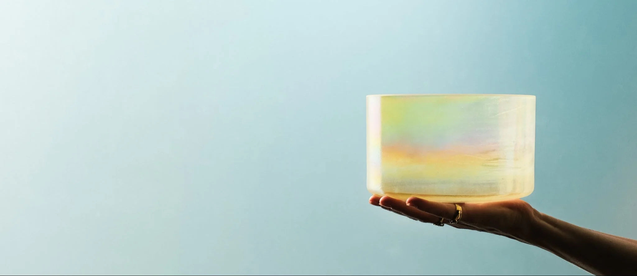 Hand holding a shimmering crystal singing bowl against a bright background – premium header image