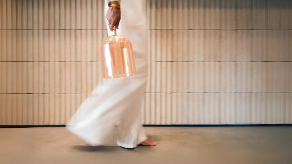 Lydia walking barefoot holding a crystal singing bowl – modern wellness setting